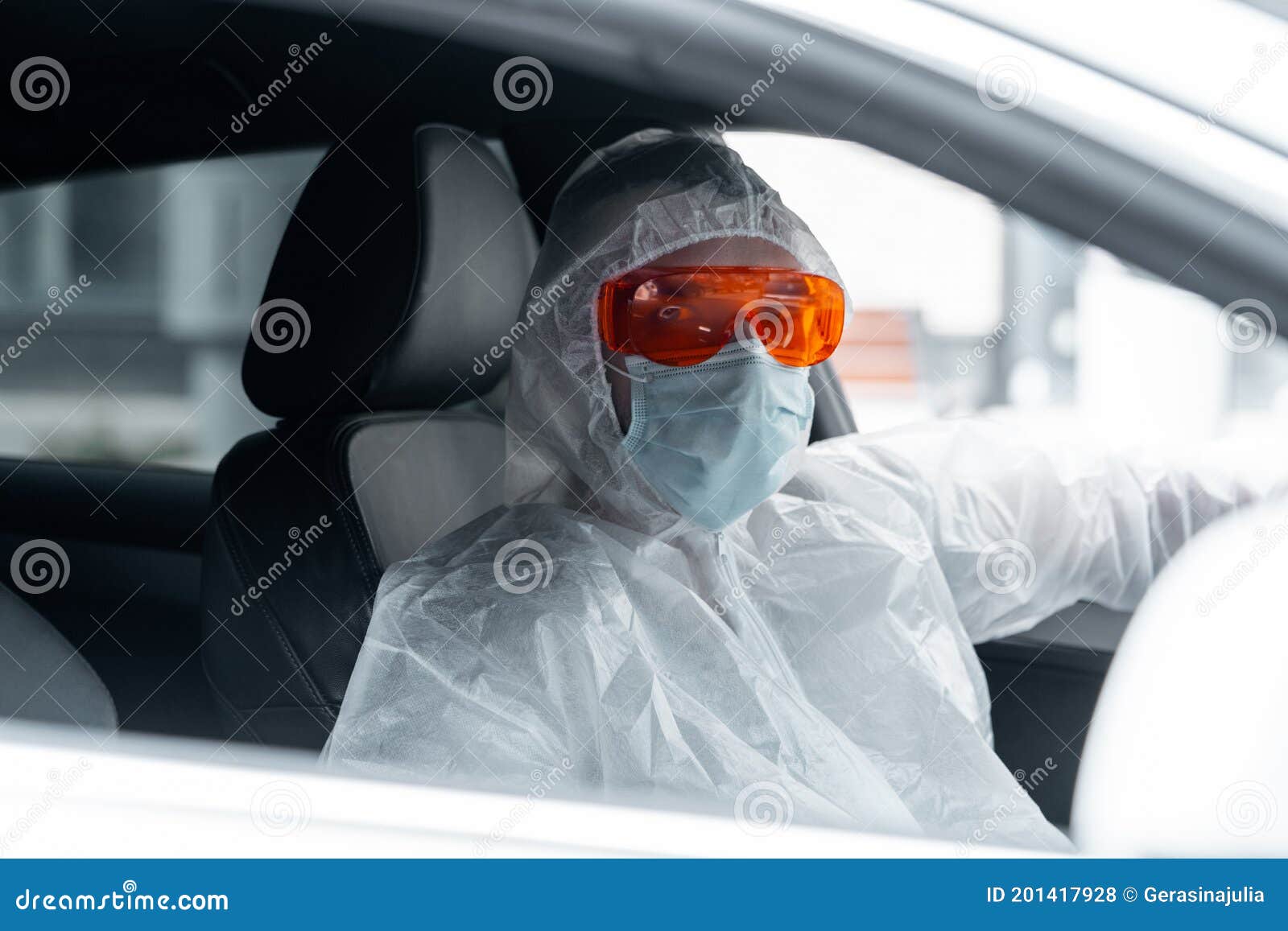 man wearing anti covid protective suit, glasses, medicine mask and gloves and driving. living according to new epidemia