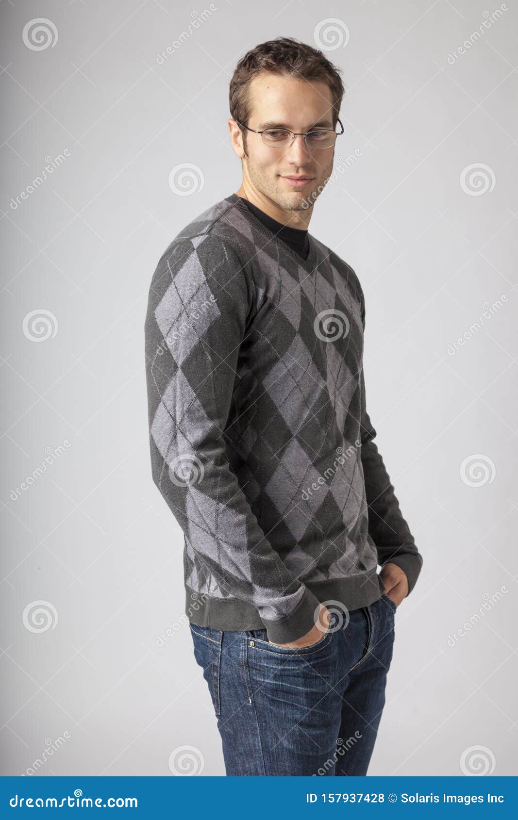 man wearing argyle sweater, jeans and eyeglasses. young men`s casual fall fashions clothing apparel styles.