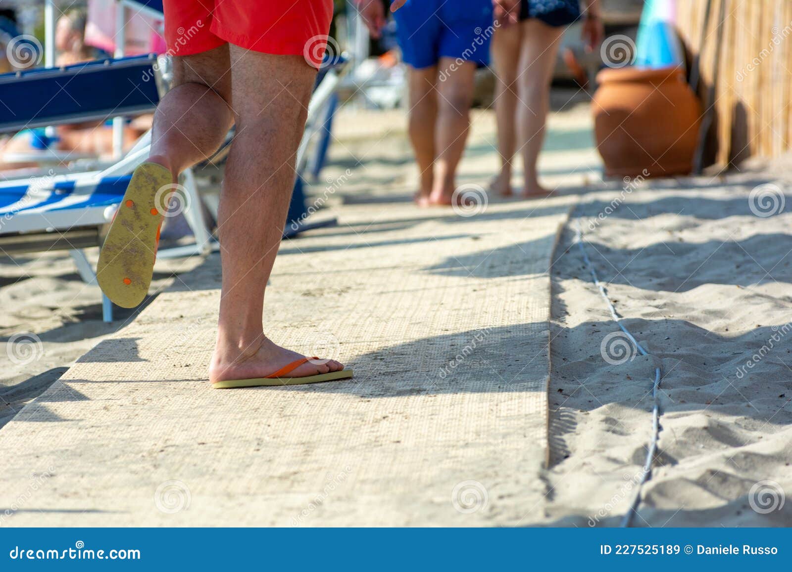 Man Wearing Flip Flops Walking on the Quay on the Beach Stock Image