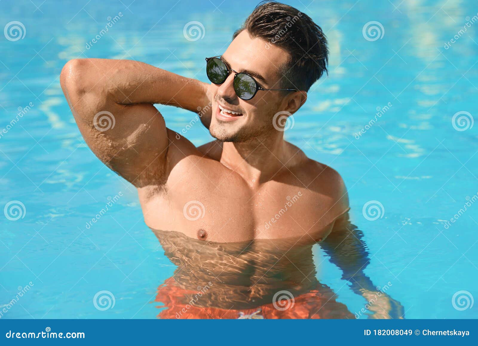Man Wearing Sunglasses with Reflection of Palm Trees in Pool on Sunny