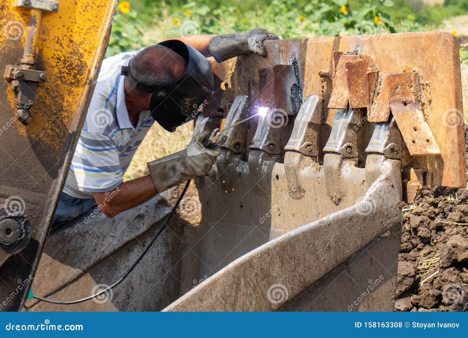 Man Welding an Excavator Bucket Outdoors Stock Photo Image of field