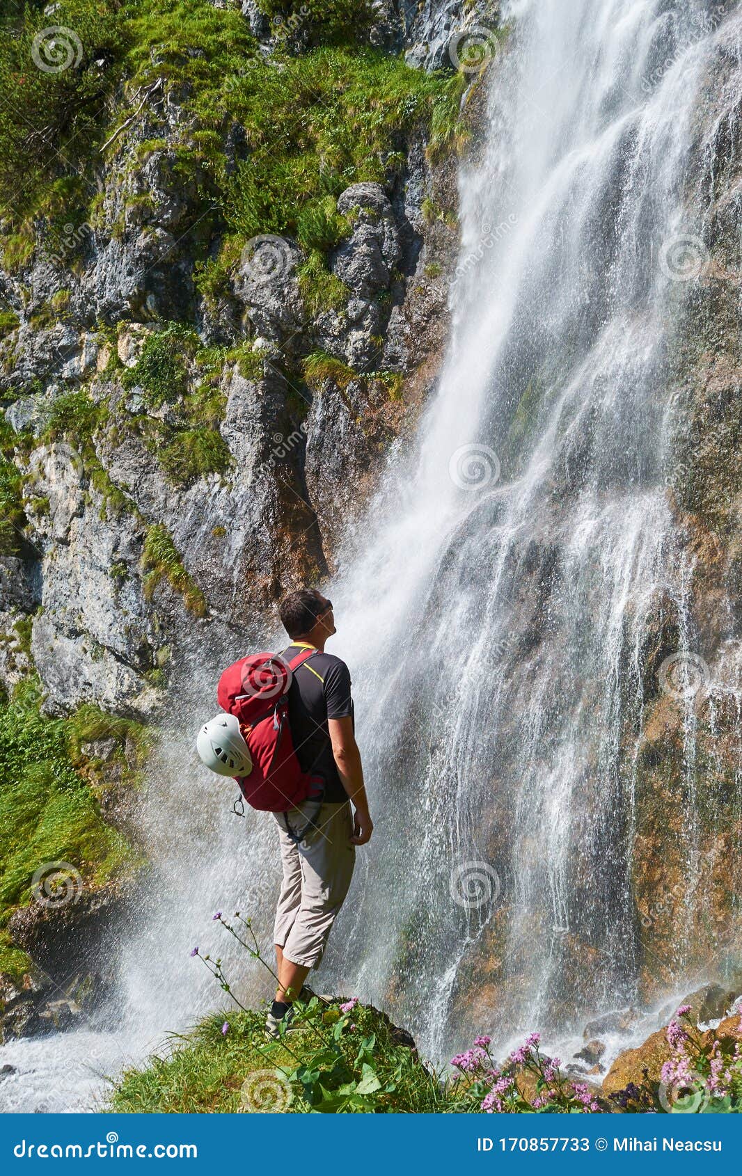 man with white helmet on its red bacpack looking up at the dalfazer waterfall dalfazer wasserfall above achensee, austria