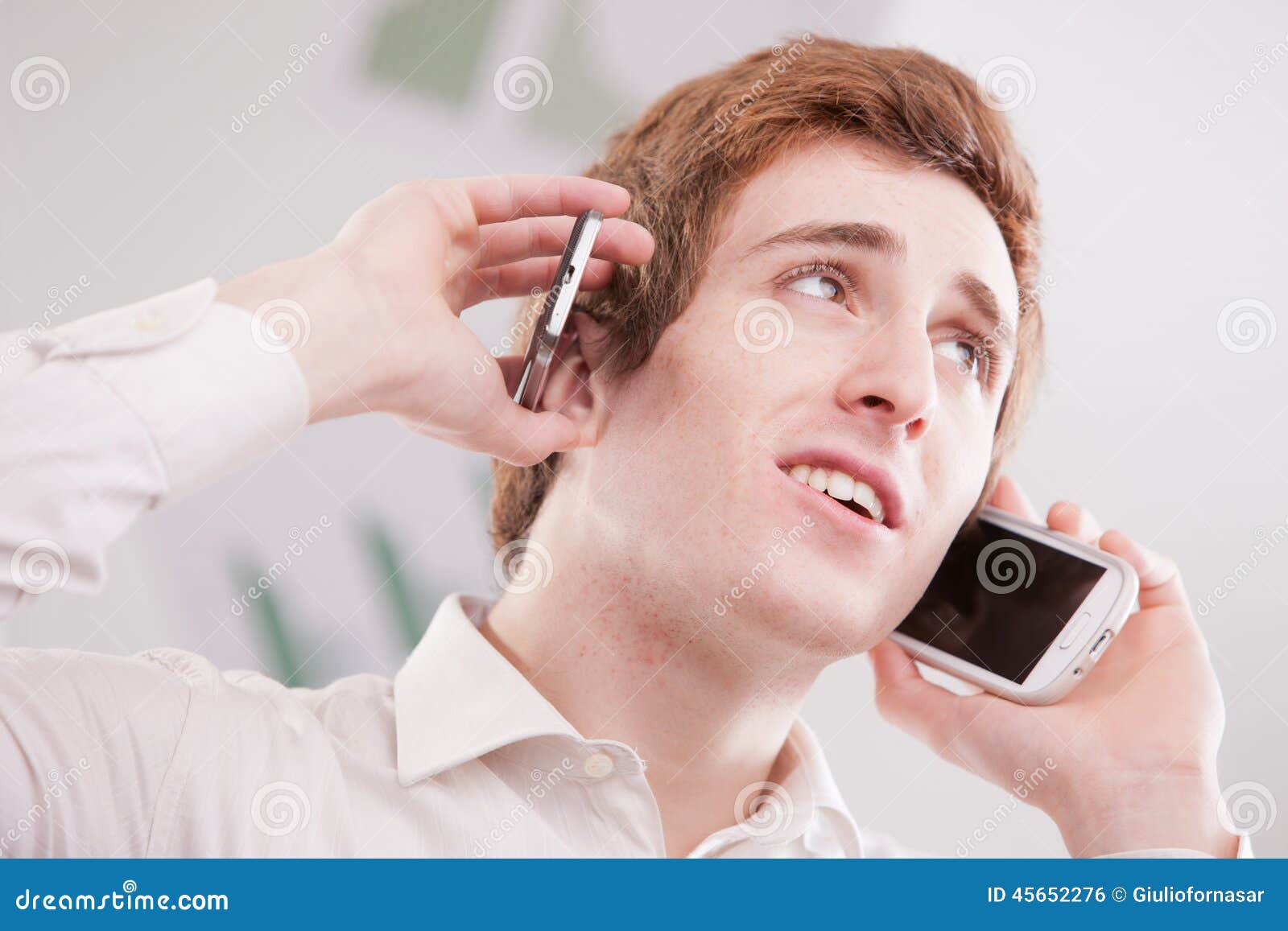 man-white-two-mobile-phones-holding-cell-to-his-ears-multitasking-calling-listening-45652276.jpg