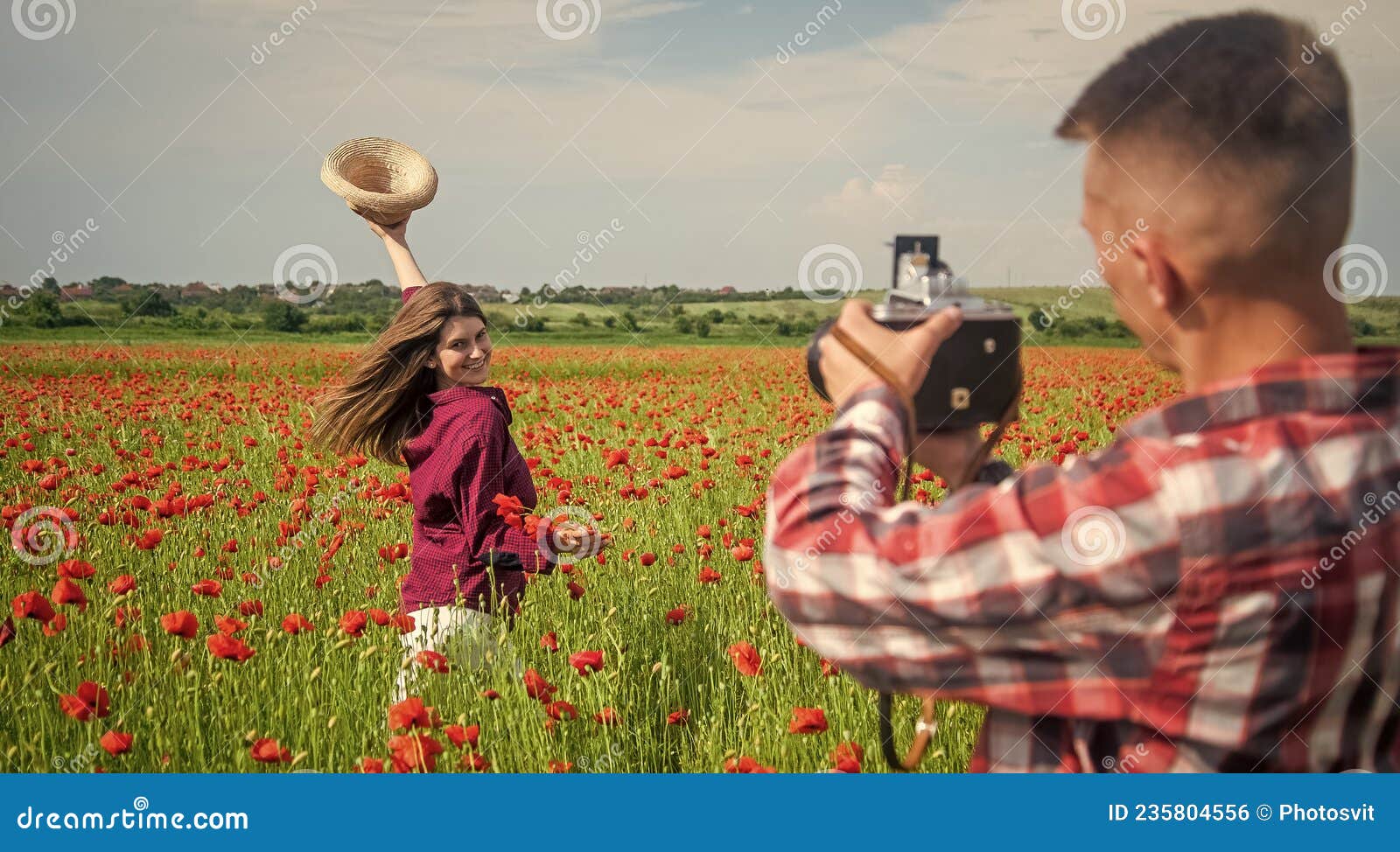 man and woman having romantic date in poppy flower field with photo camera, photographing