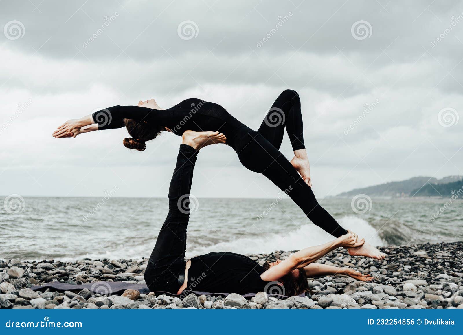 Man and Woman in Black Sport Clothes Doing Acroyoga on a Sea Beach