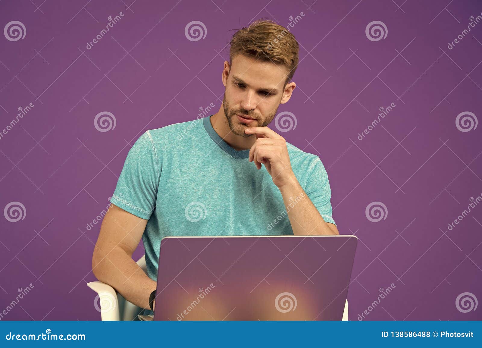man work on laptop on violet background. guy in blue tshirt with computer on purple background. internet surfing and