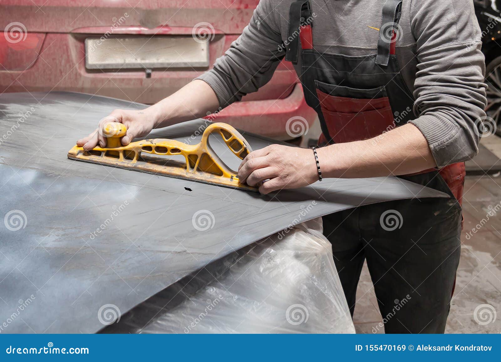 Man Worker Preparing for Painting a Car Element Using Emery Sender by a