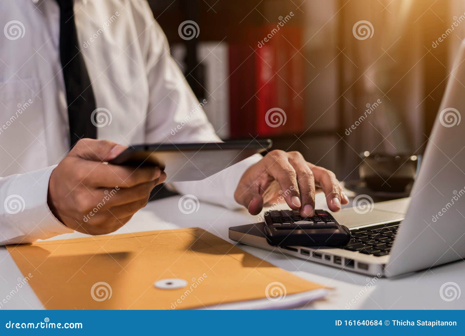 the man working on calculator to calculate financial data report, accountancy document and laptop computer at office.