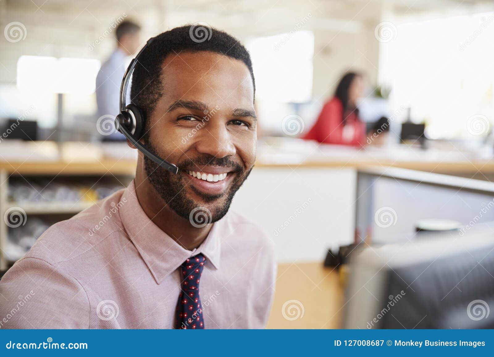 man working in a call centre smiling to camera, close-up