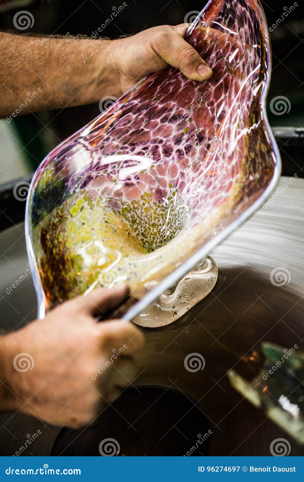 man working a glass blown vase on spinning silica sanding disk