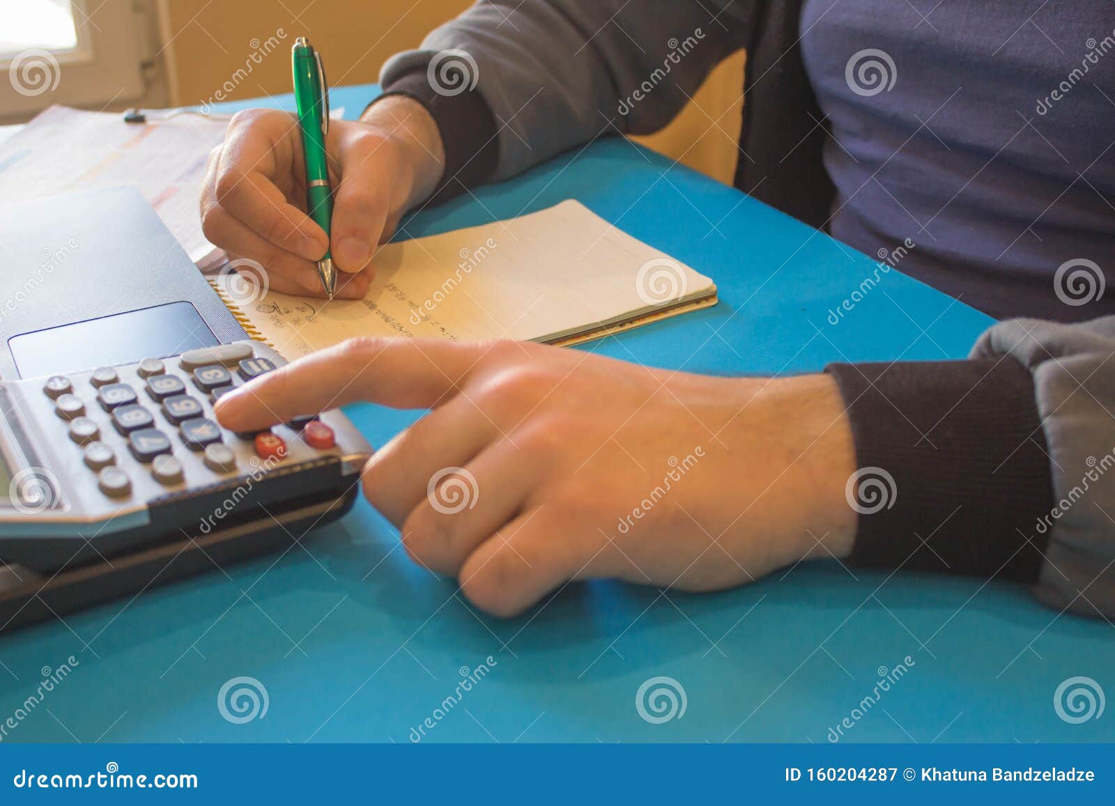 Man Writing Notes from Computer on Table. Man Hand with Pen