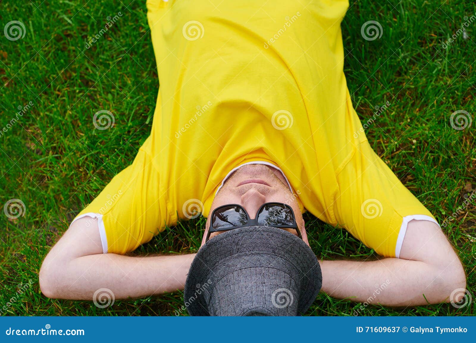 Man in a Yellow Tshirt and Hat Lying on the Grass Stock Image Image