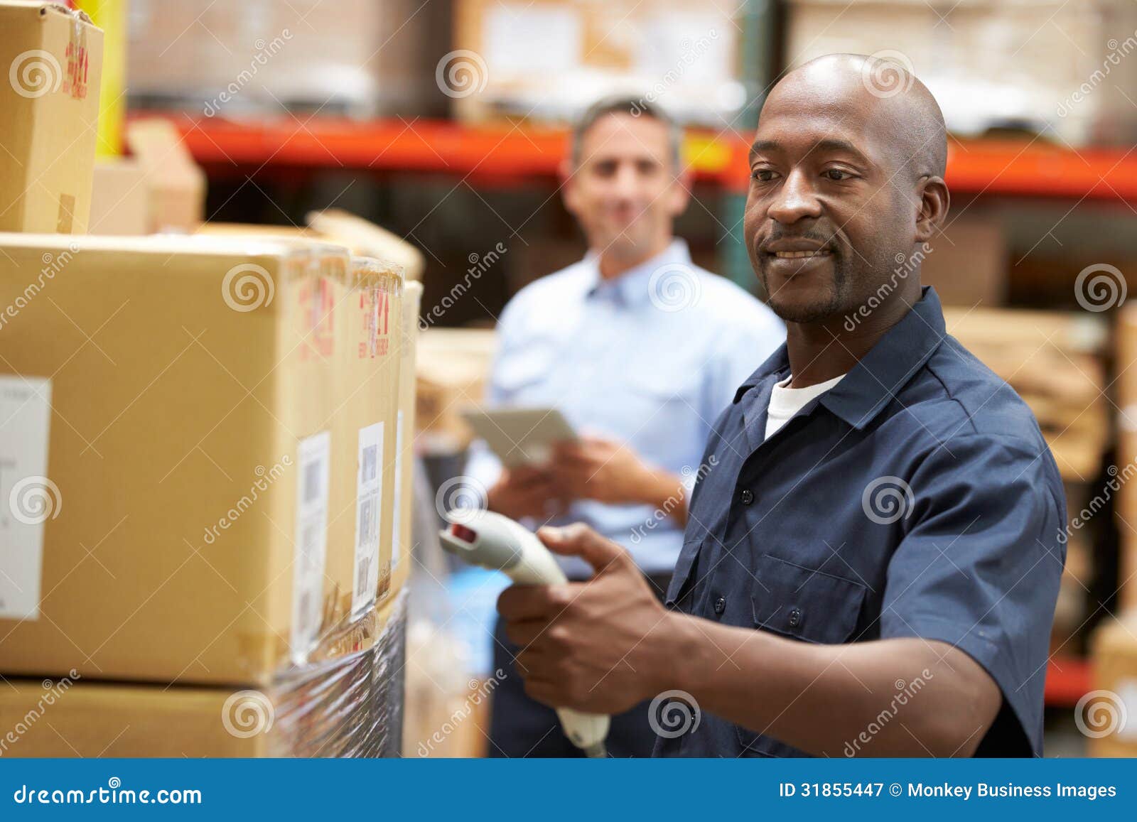 manager in warehouse with worker scanning box in foreground