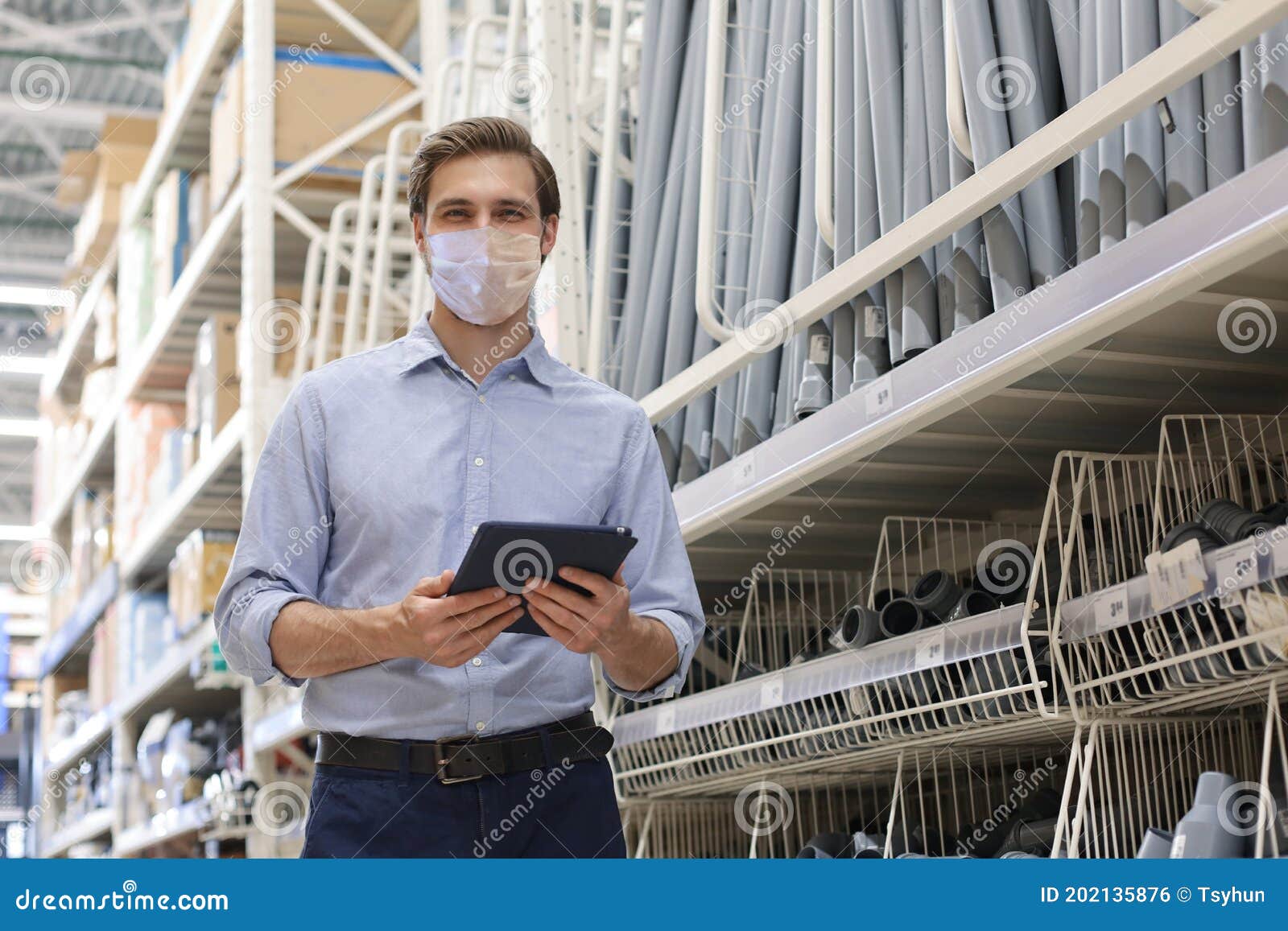 manager wears preventive mask use his tablet for online checking products available