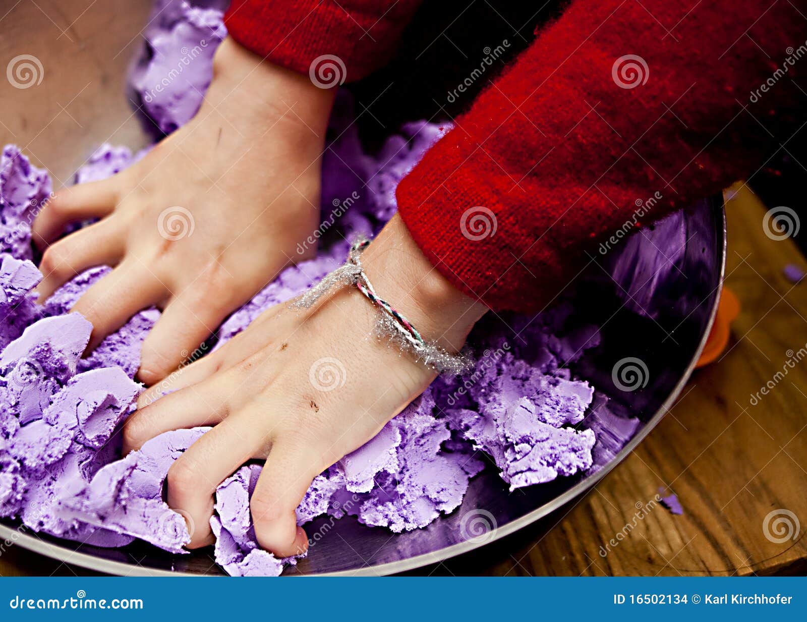 Mani occupate. Un accoppiamento delle mani del bambino che mescolano la lavanda ha colorato la pasta