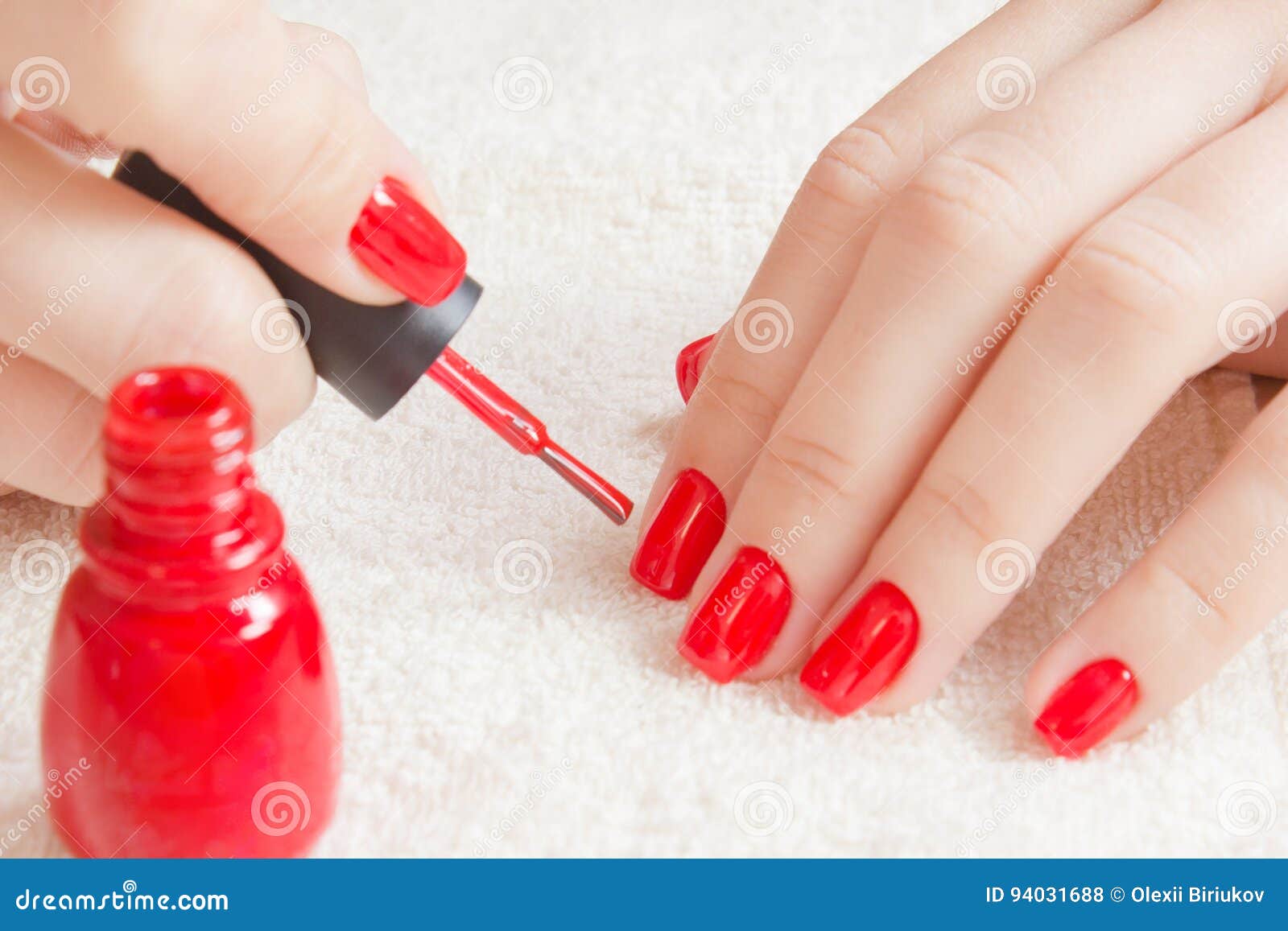 manicure - beautiful manicured woman`s nails with red nail polish on soft white towel.