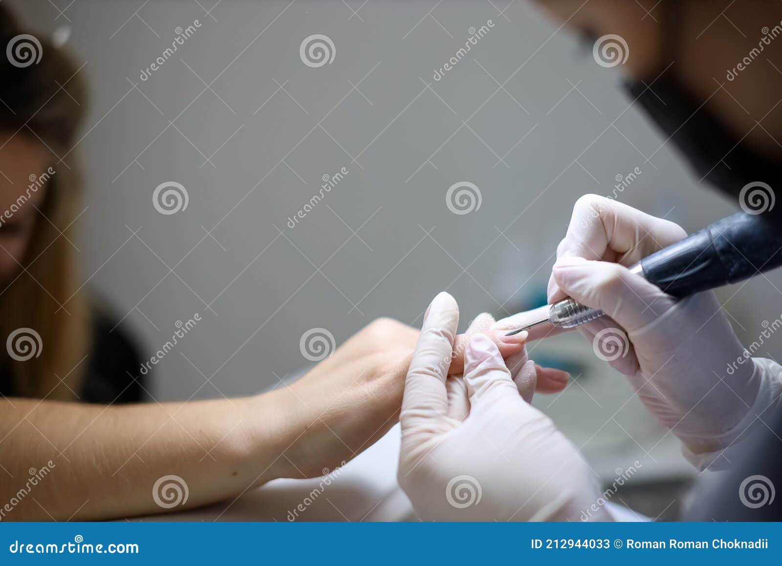 Manicure Master Processes the Client`s Nails with a Nail Grinding