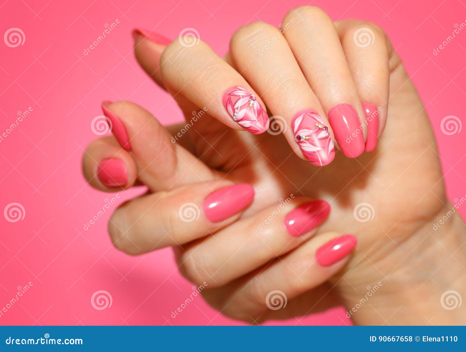 manicured woman`s nails with pink nailart with flowers.