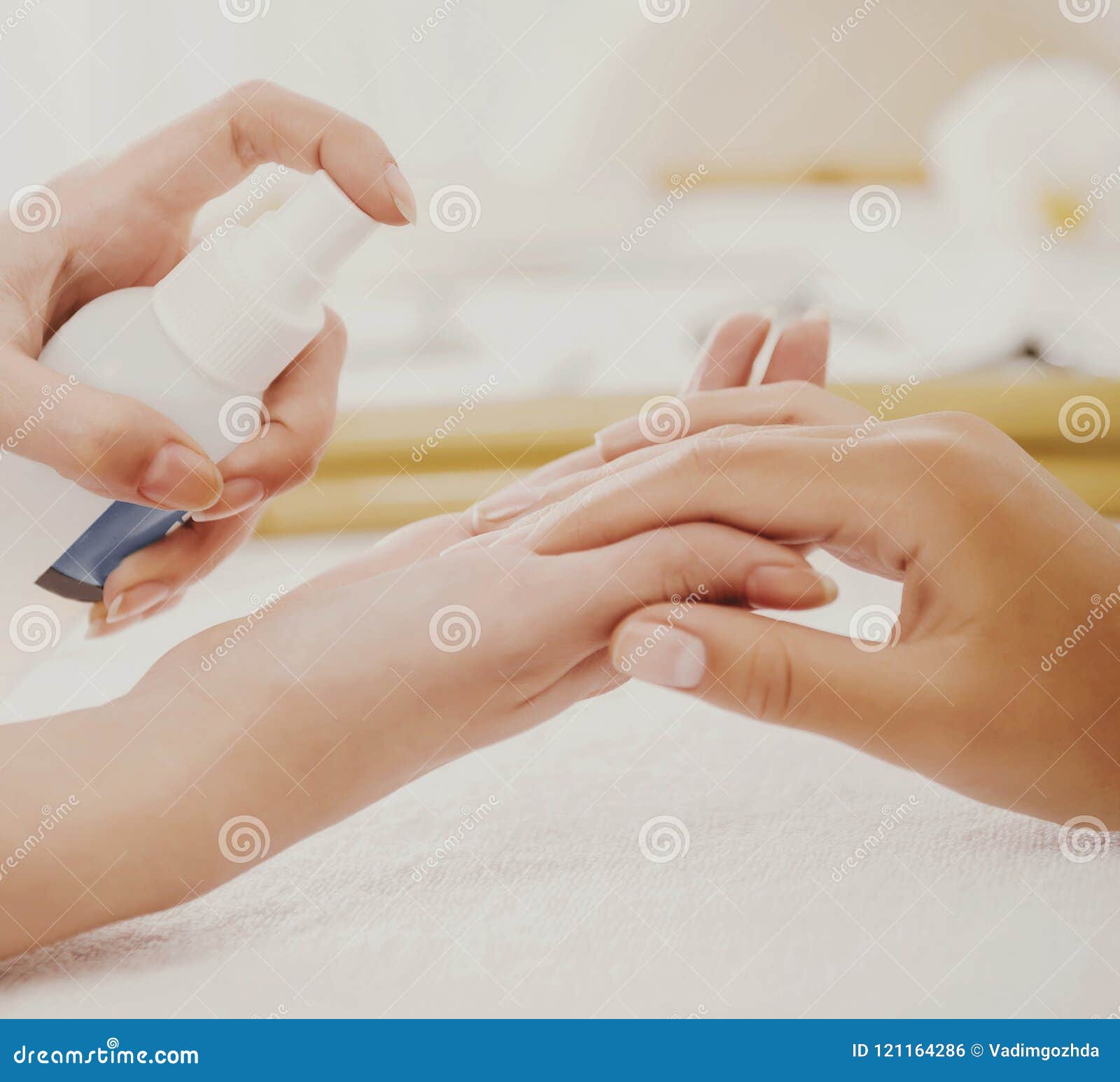 manicurist applies spray to clients gentle hands.