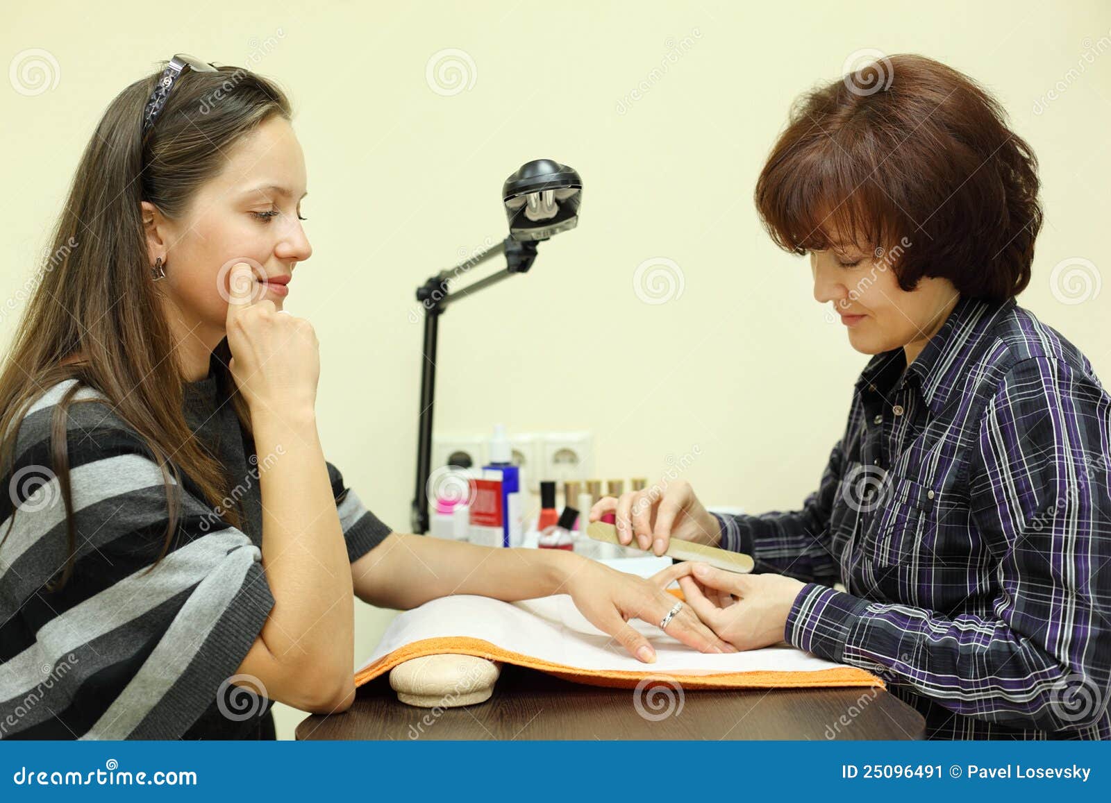 manicurist makes manicure by nailfile for woman