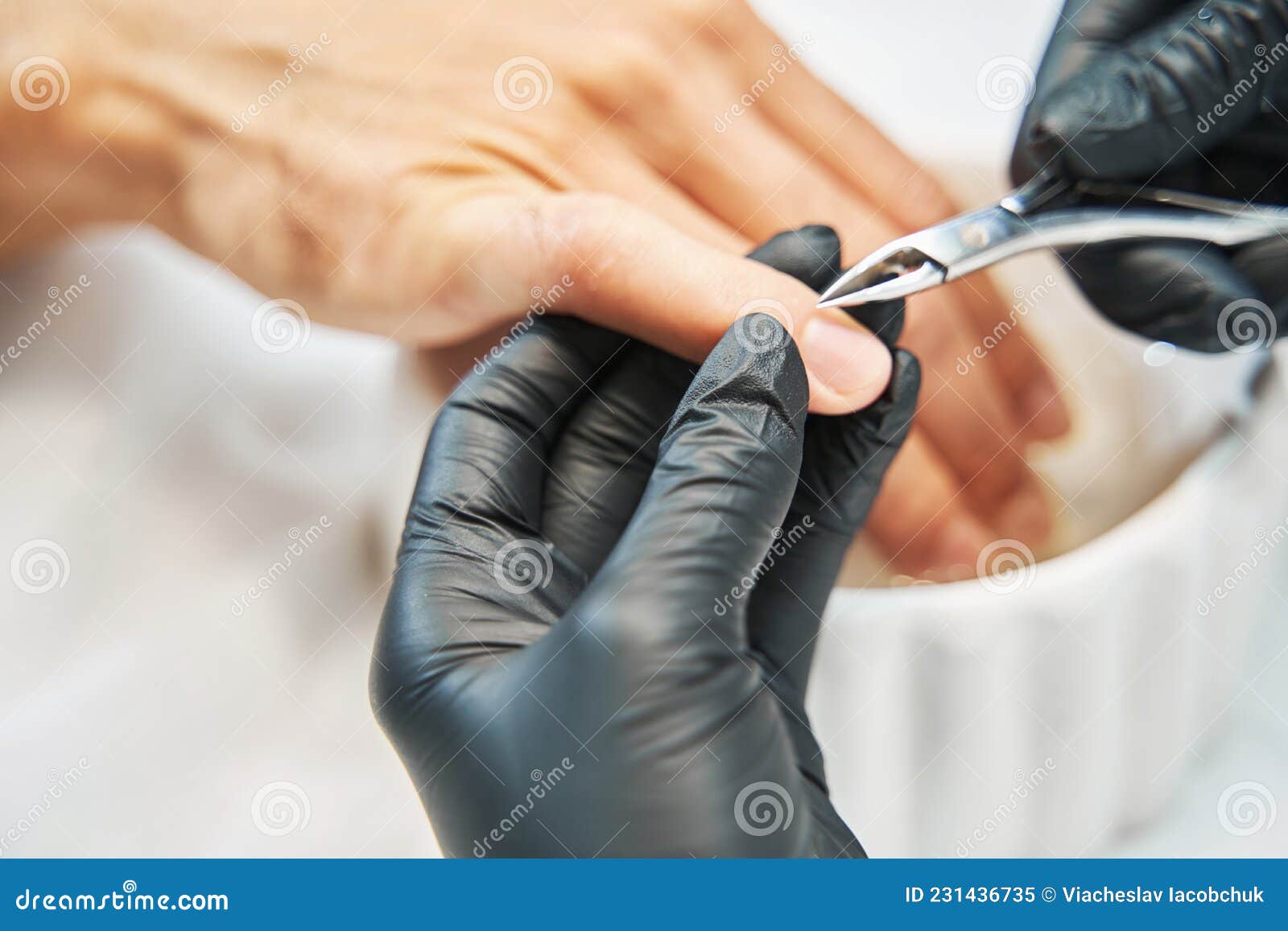 manicurist nipping away skin from nail with cuticle cutter