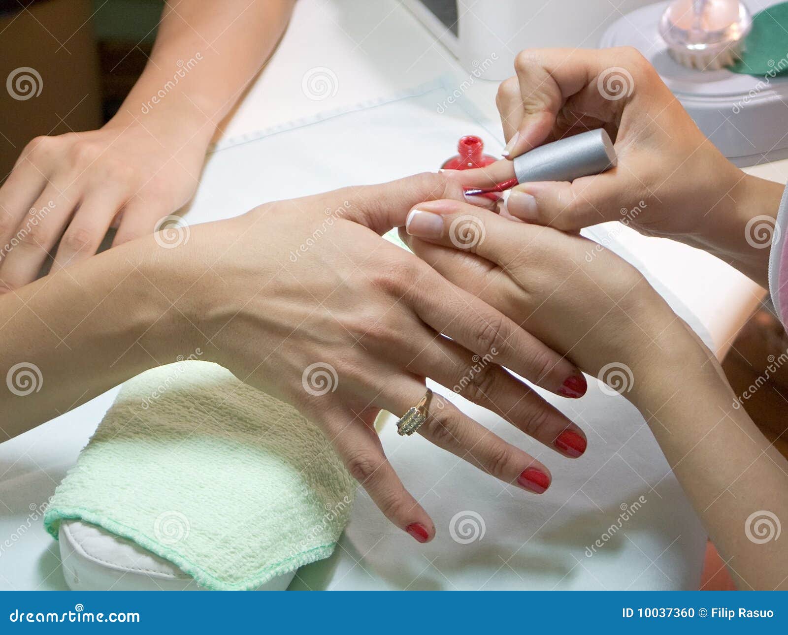 manicurist putting red nail polish