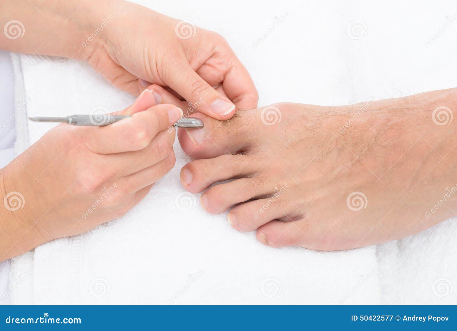 manicurist removing cuticle from the nail