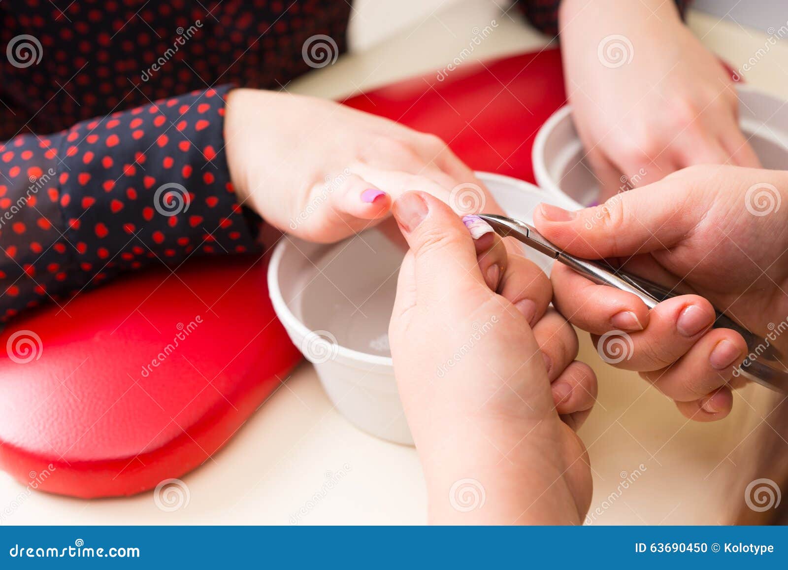 manicurist trimming cuticles on client hands