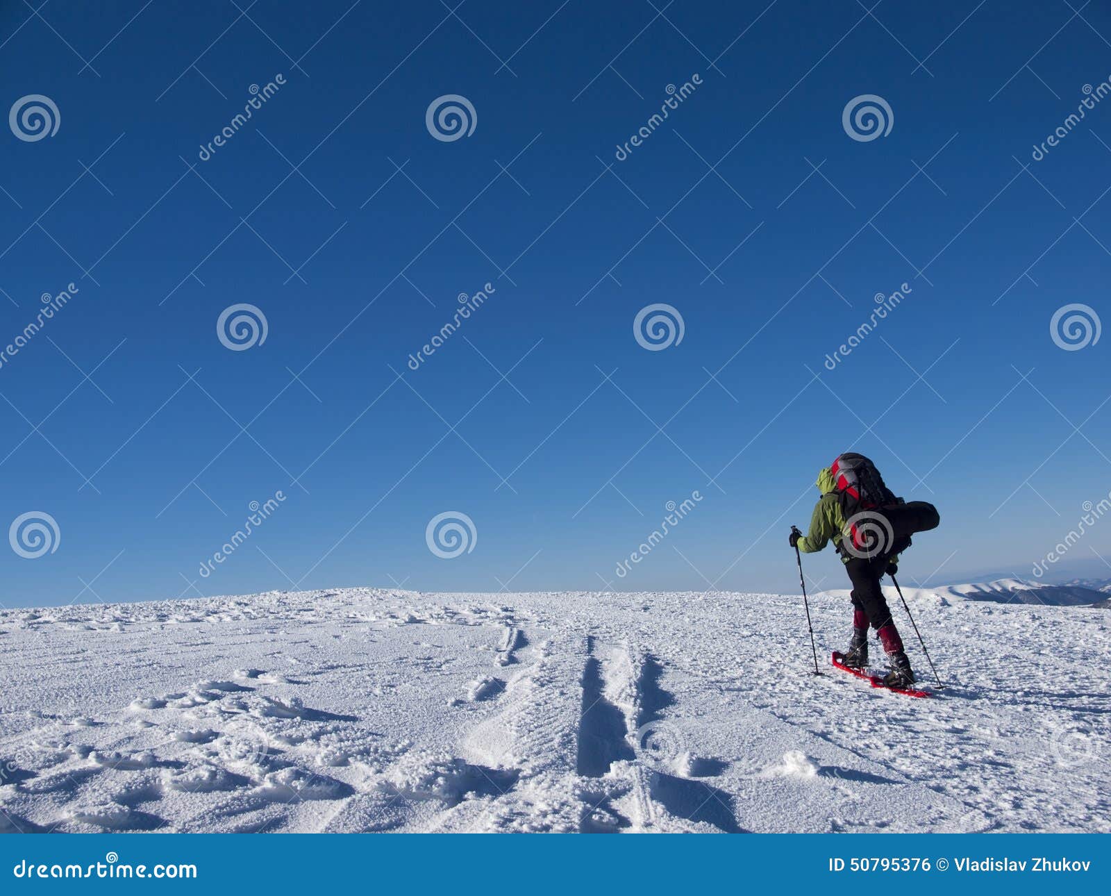 Mannen i snöskor i bergen. Mannen i snöskor och med trekking poler är i bergen