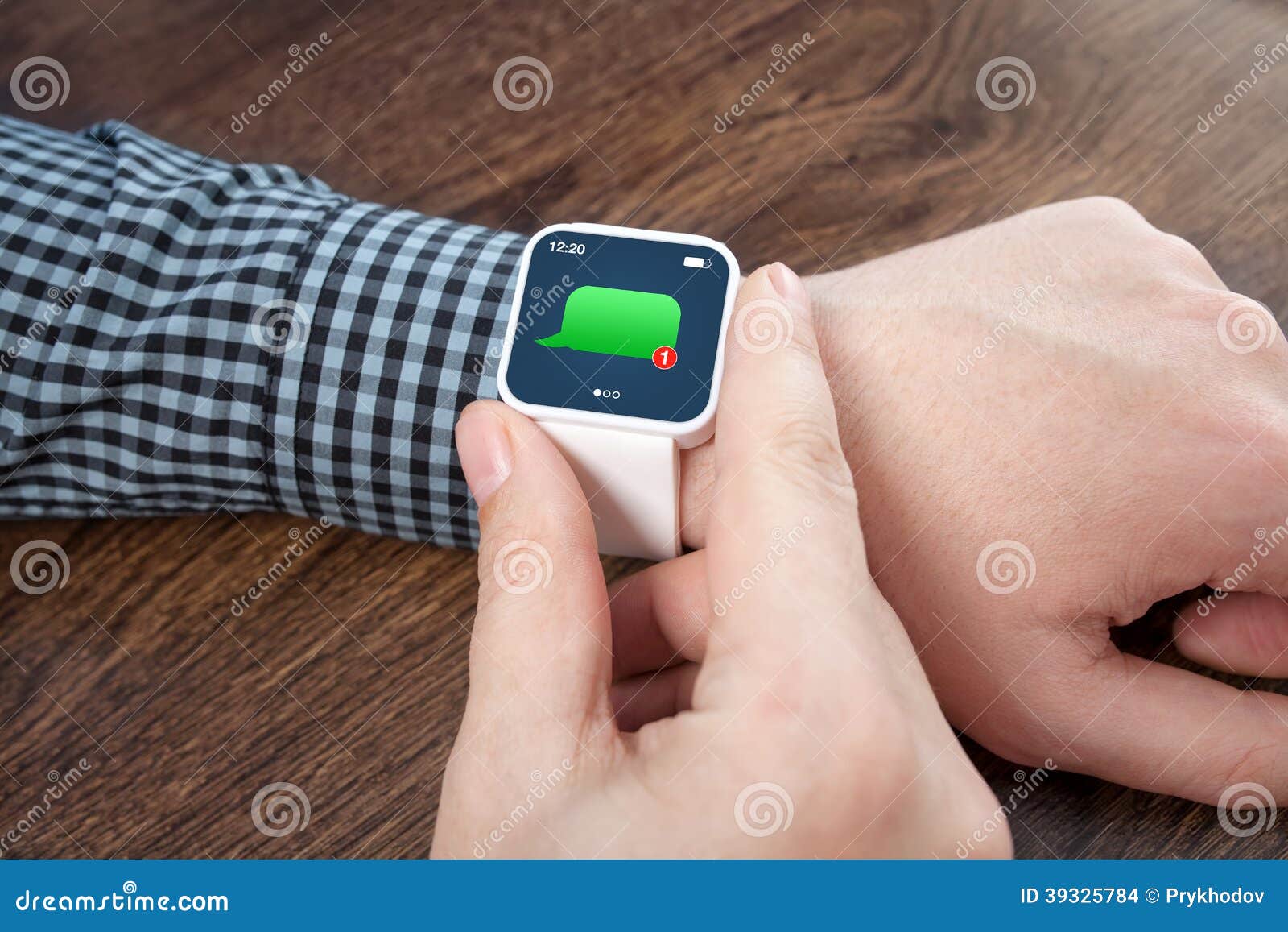 Manos masculinas con el reloj elegante blanco con el mensaje en la pantalla. Manos masculinas con el smartwatch blanco con el mensaje en la pantalla sobre una tabla de madera en una oficina