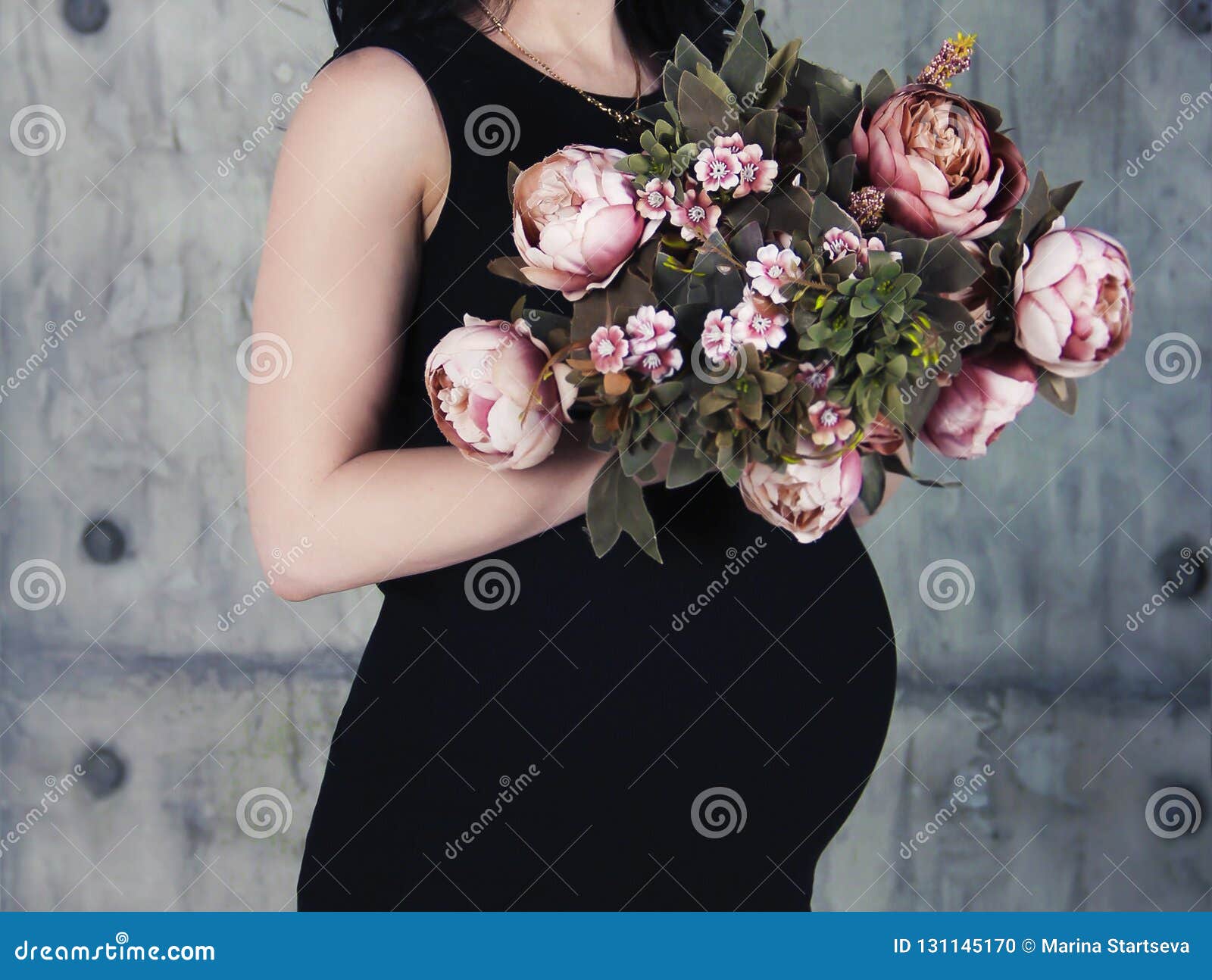 Manos Y Vientre De Una Mujer Embarazada Con Un Ramo De En Ropa Negra Foto de - de flor, gente: 131145170