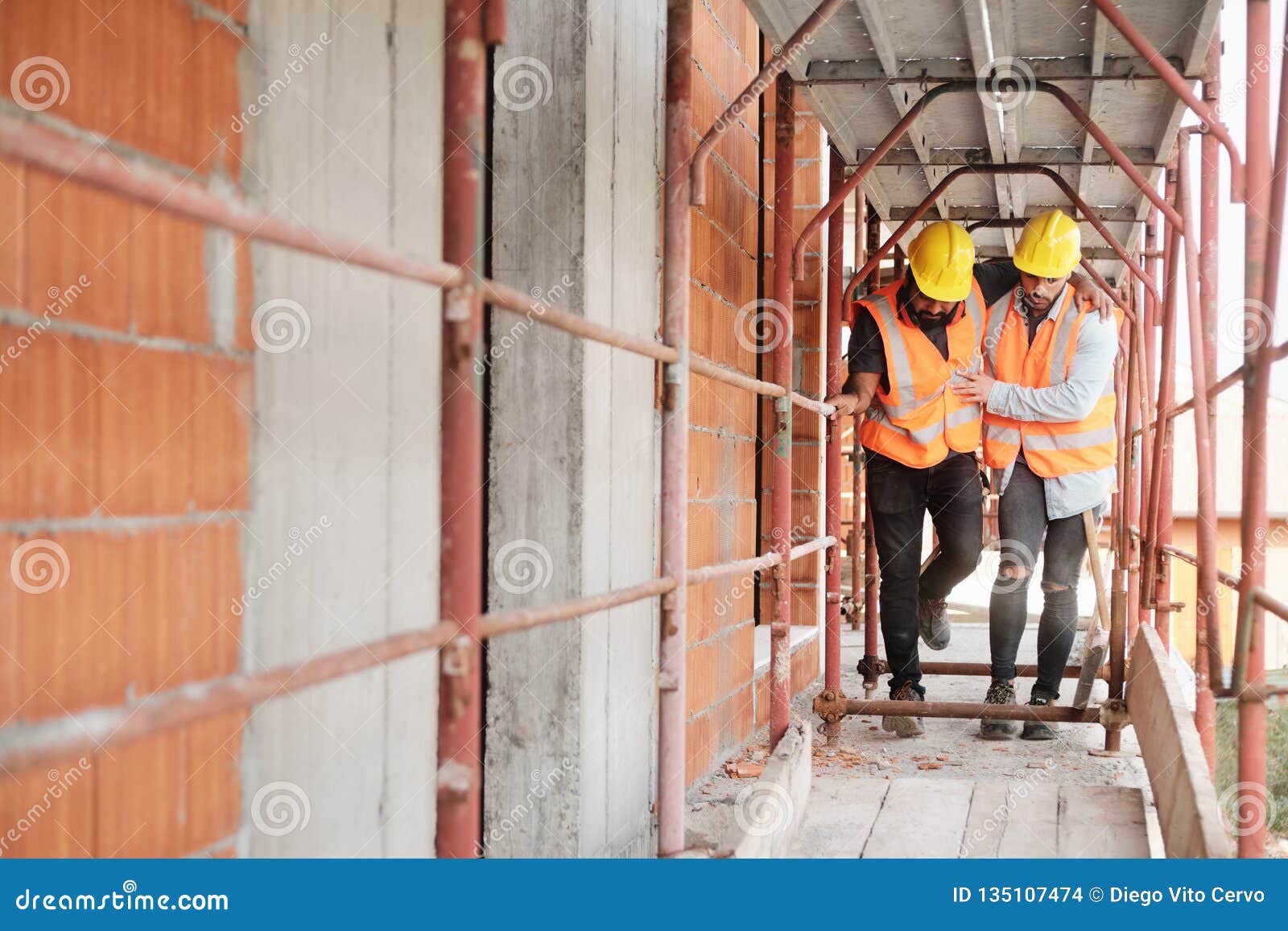 manual worker helping injured colleague in construction site