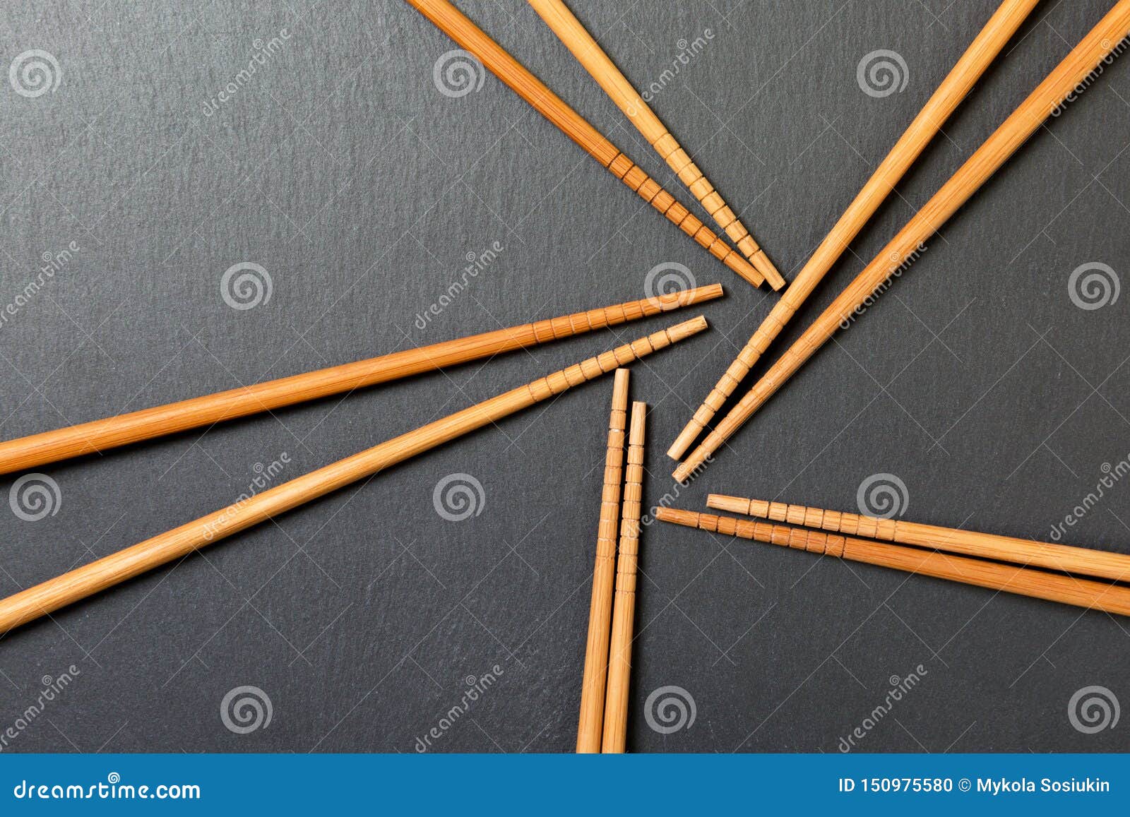 many bamboo chopsticks on black slate background, textured, top view with opy space