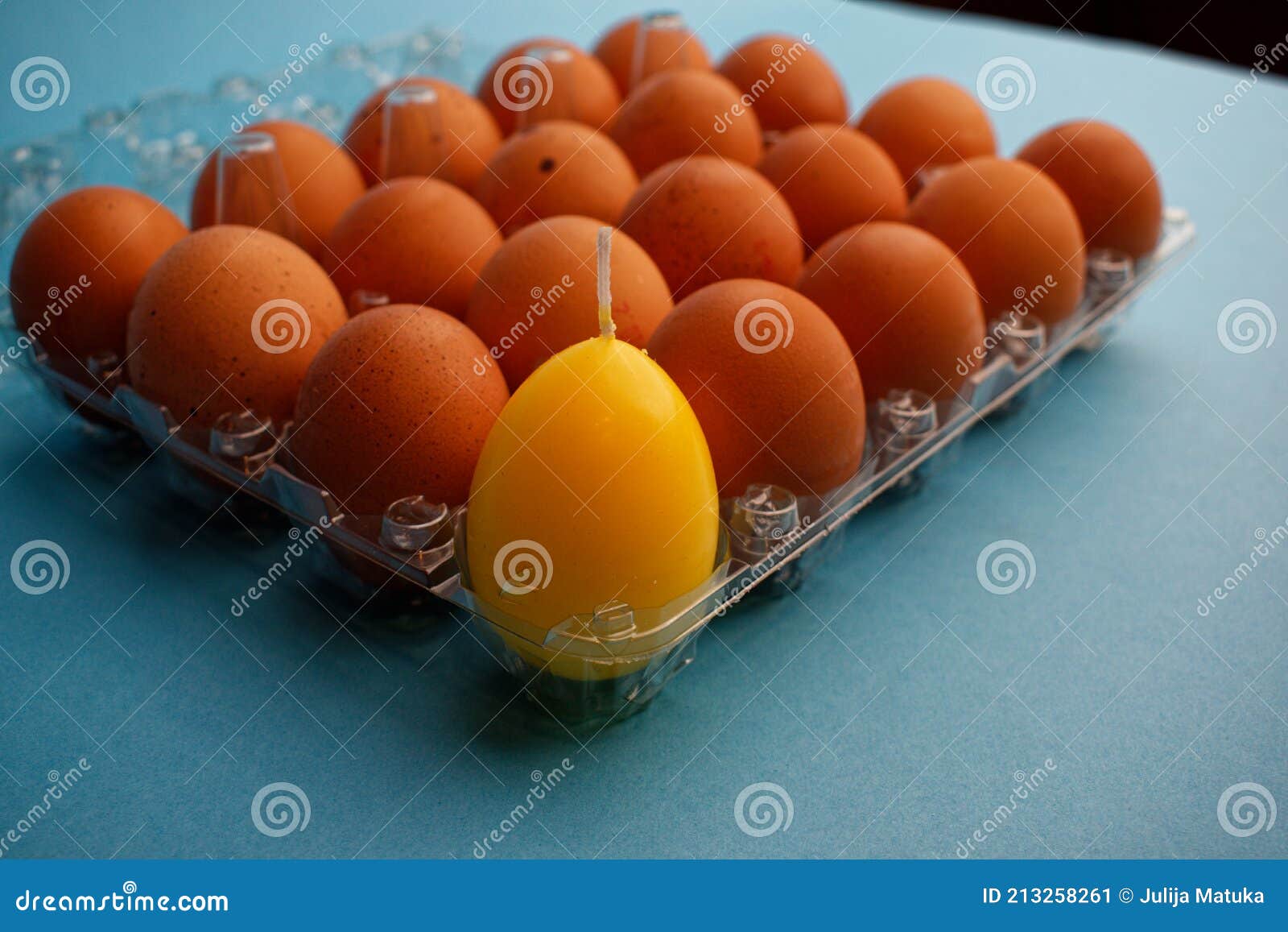 Many Brown Eggs and One Yellow Eggshaped Candle in a Special Plastic