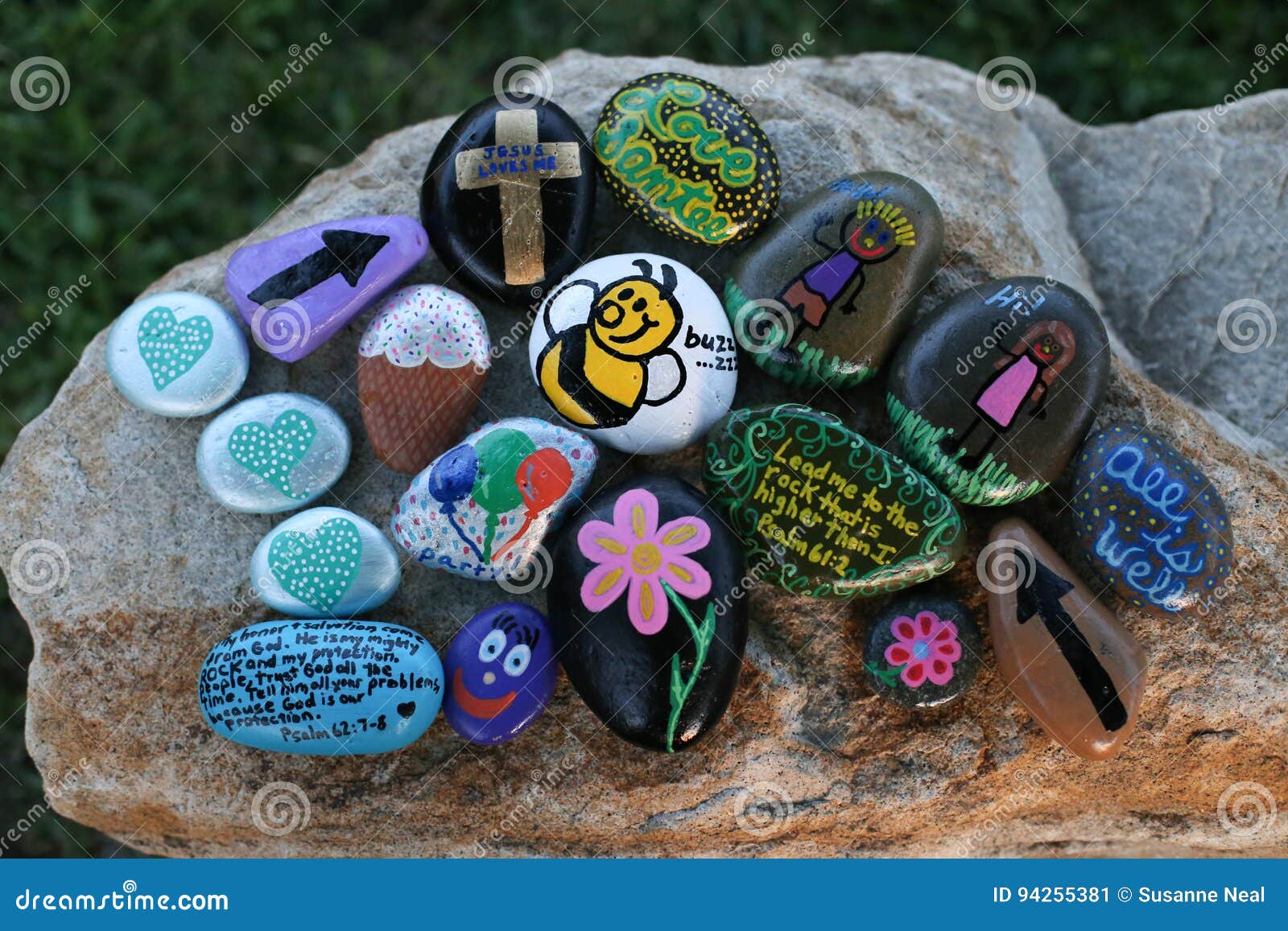 many decorated painted rocks displayed on a small boulder