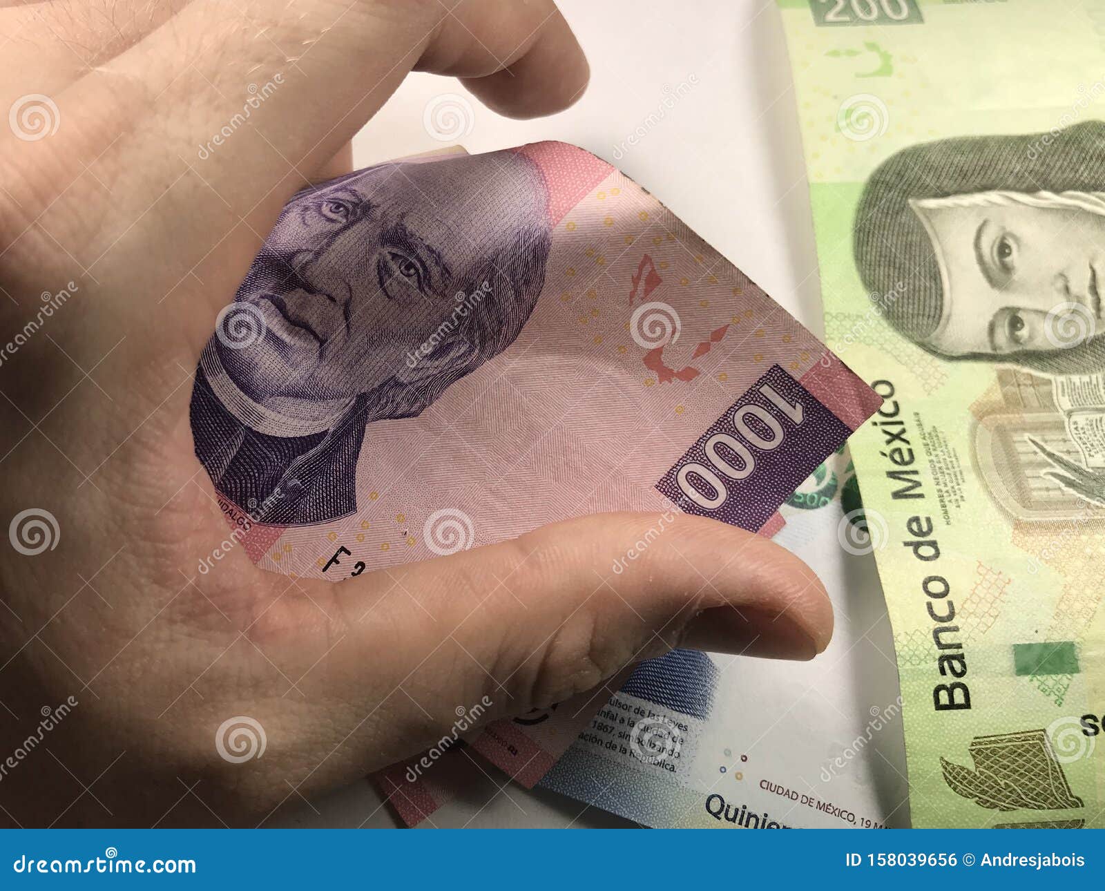 Mexican Peso Bills Spread Randomly Over a Flat Surface with a Hand Over