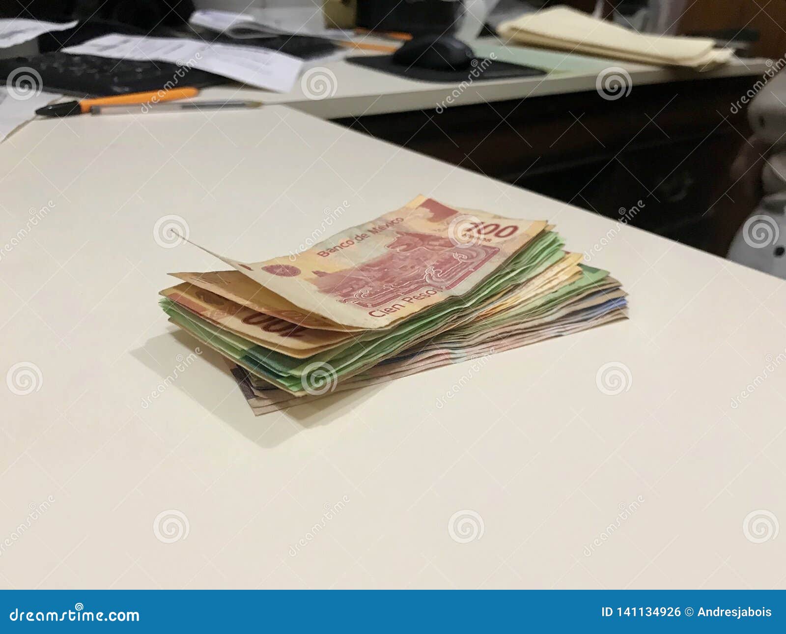 many mixed mexican peso bills spread over a beige desk
