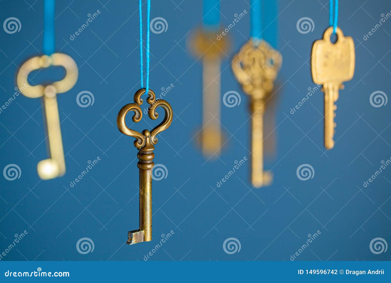 Ключ из желтого металла. Ключи весят. Много ключей на нитке. Ключ весит на верёвке.