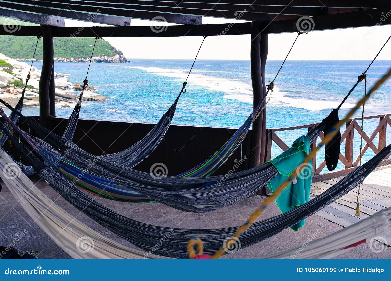 many relaxing hammocks under a bungalow, with a blurred ocean background in tairona national park, colombia