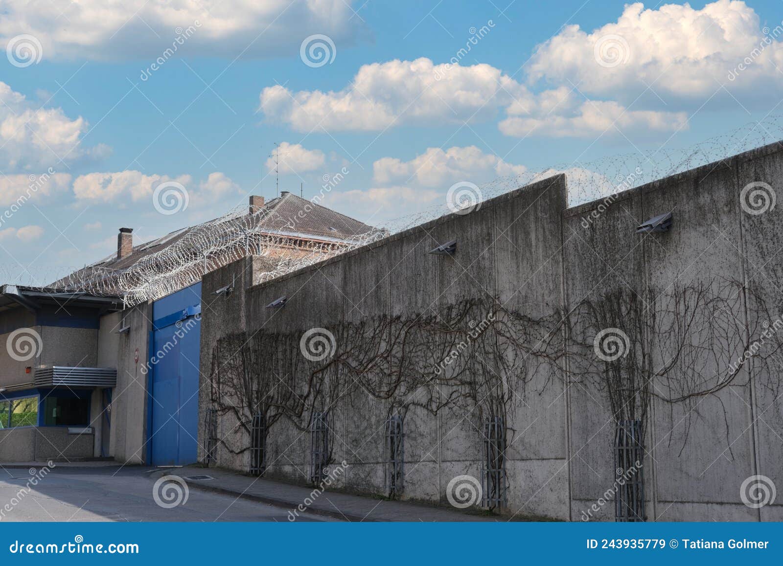 many rows of barbedwire, high concrete fence, barbed wire fence on top, building for execution of punishments for criminals,