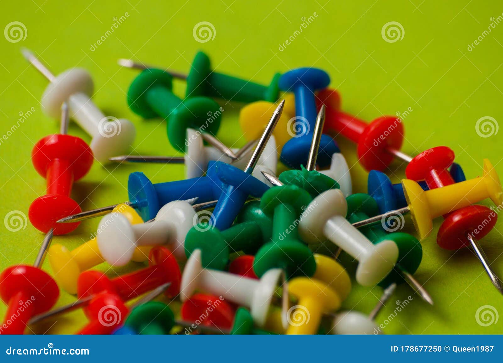 Many Thumbtacks of Different Colors on Green Designer Paper Stock Photo