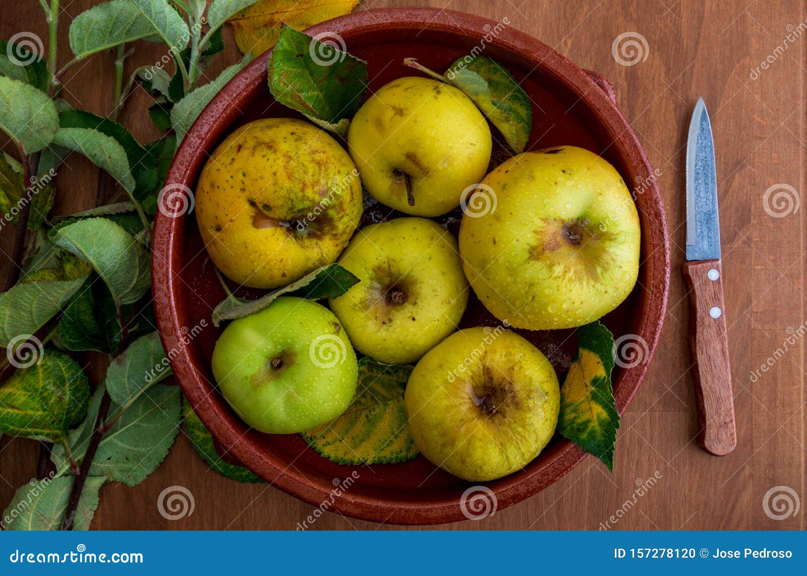 manzanas amarillas reinetas frescas, crudas y maduras. con hojas sobre sobre fondo de madera.