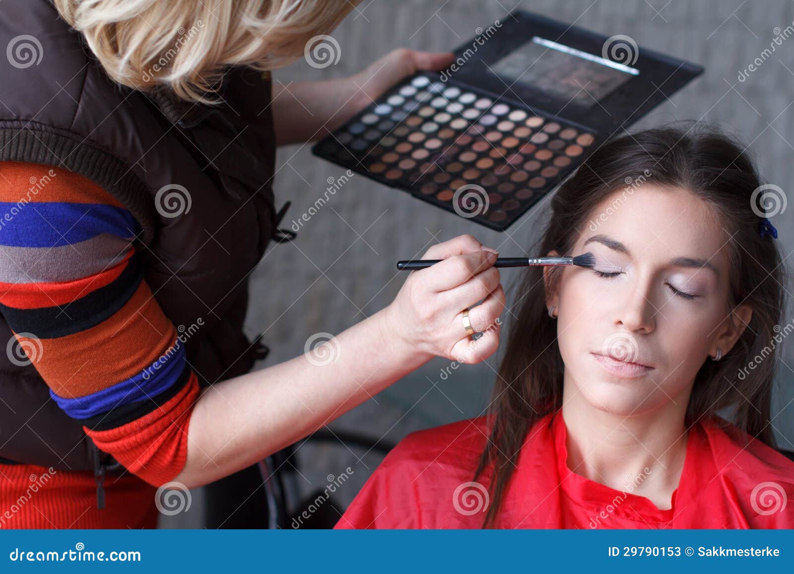 Maquilhador que prepara a sombra modelo triguenha atrativa antes da sessão fotográfica