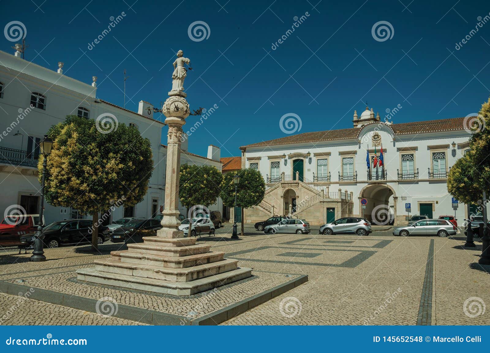 marble pillory with sculpture in square and city hall in the back