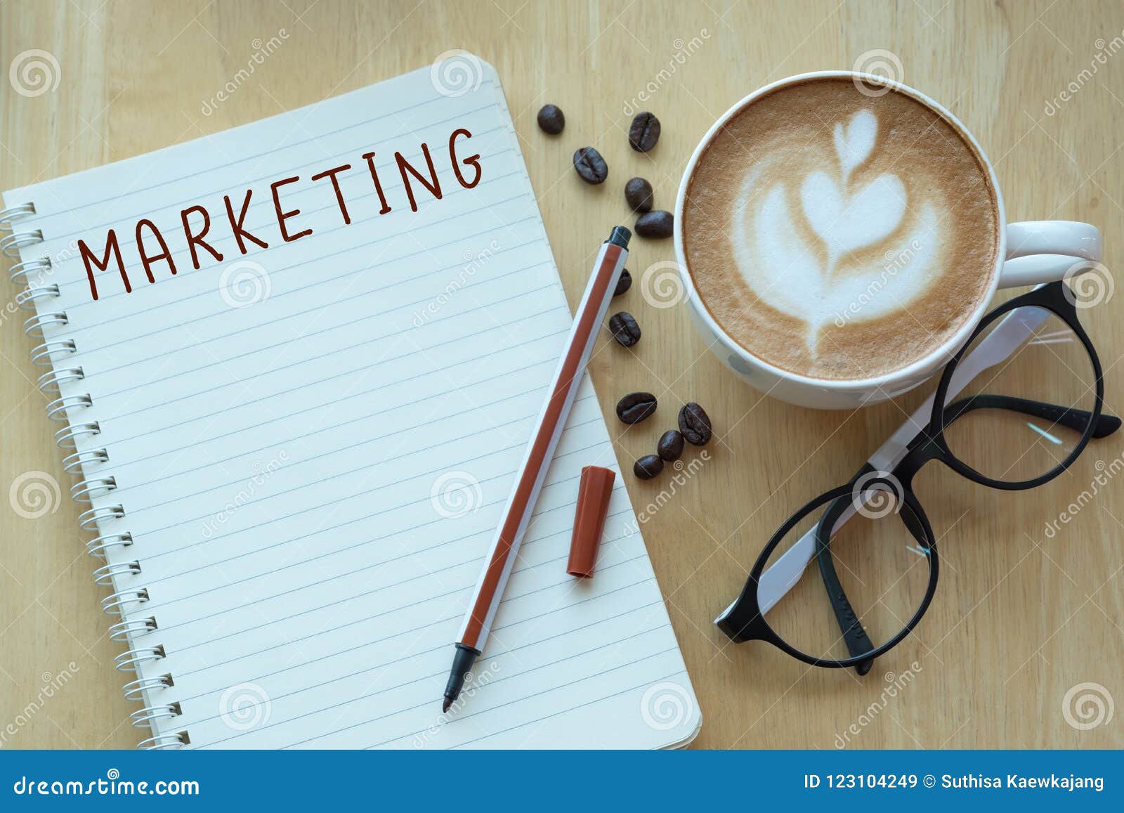 marketing on note book with coffee cup, top viwe on wooden pine