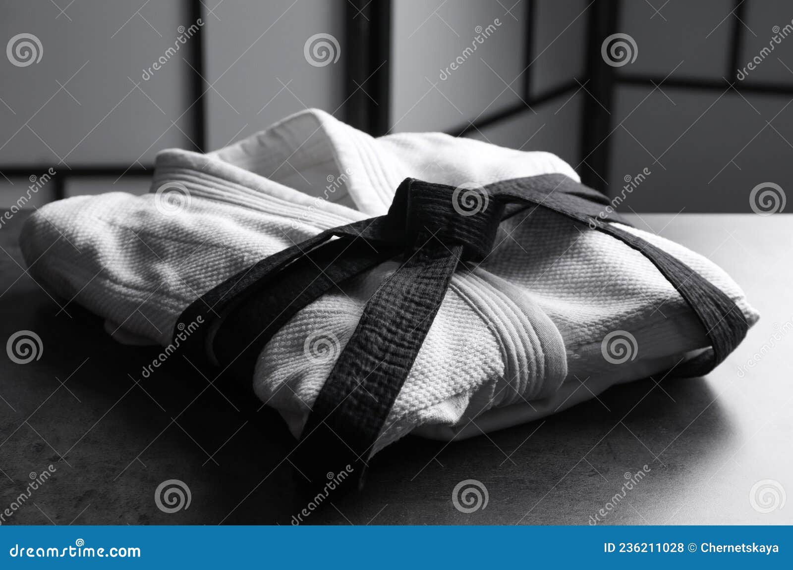 Martial Arts Uniform with Black Belt on Grey Stone Table Indoors Stock