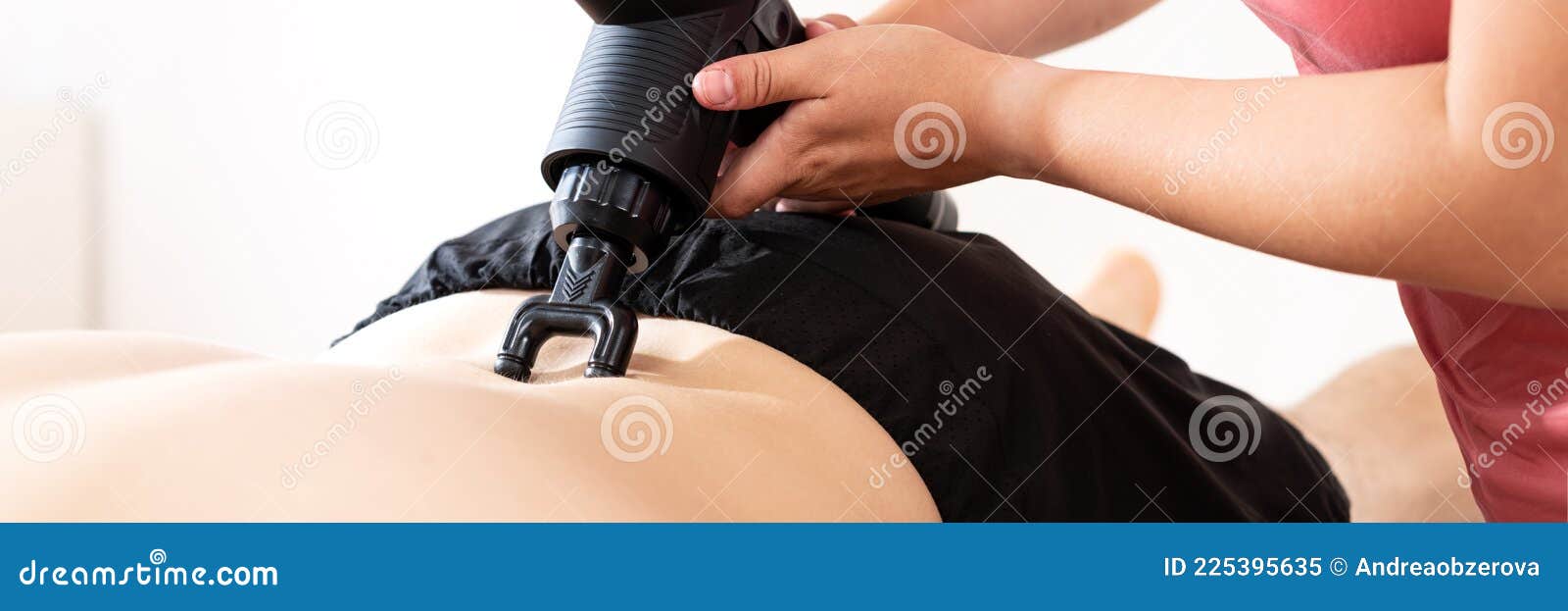 massage gun background. young female physiotherapist using handheld massaging gun to relieve lower back pain.
