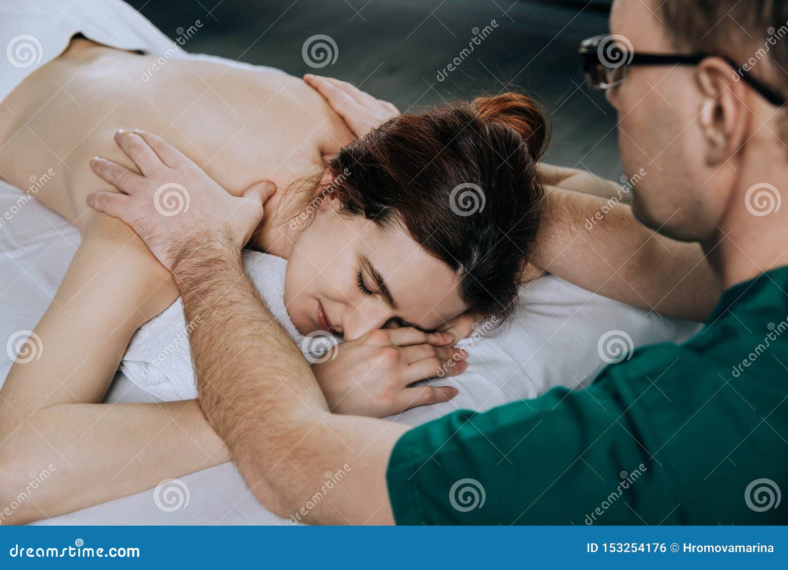 massage therapist doing shoulder massager of a young woman. beautiful relaxed face of a young woman with brown hair