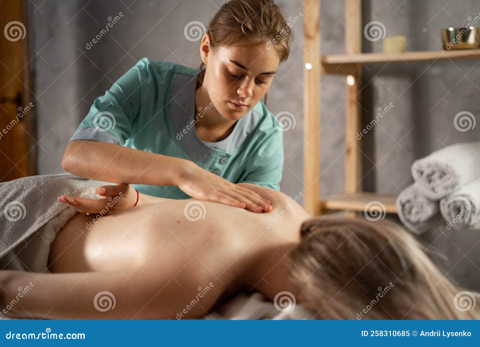 masseur massaging shoulder of young woman. female patient getting remedial body and shoulder blade massage easing pain