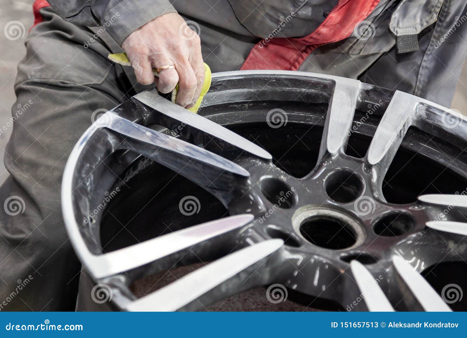 master body repair man is working on preparing the surface of the aluminum wheel of the car for subsequent painting in the